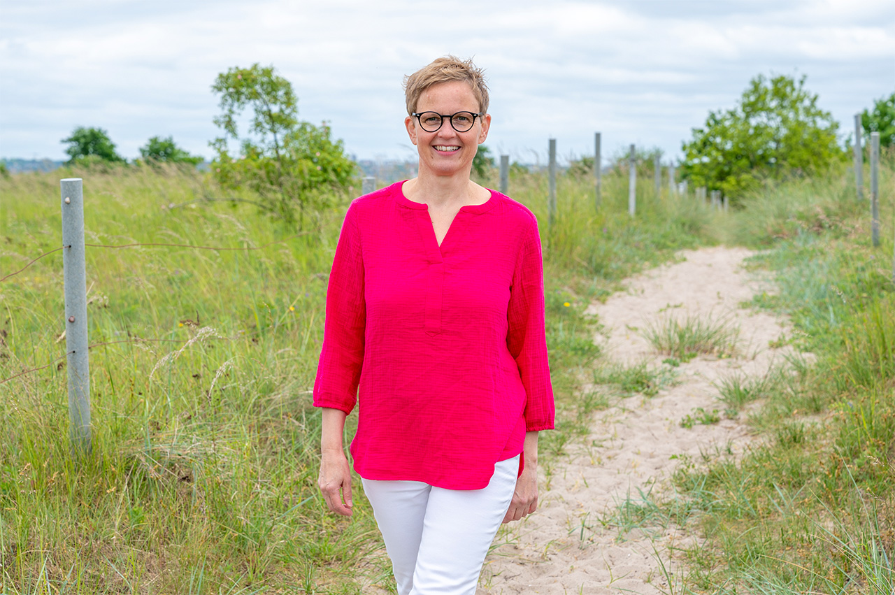 Achtsamkeitstraining in Kiel Symbolisch für Achtsamkeitstraining: Marlene Rostig läuft durch die Dünenlandschaft, im Hintergrund Sandweg